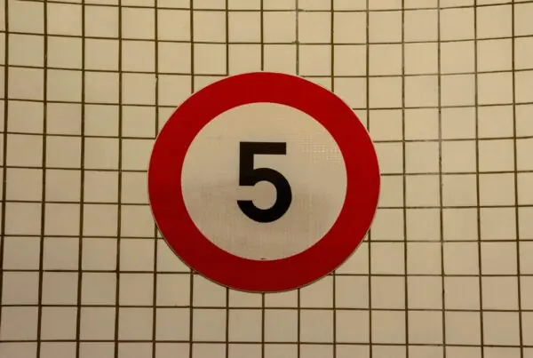 Nummer 5 in een circkel met een rode rand en witte achtergrond. op een geblokte witte achtergrond.